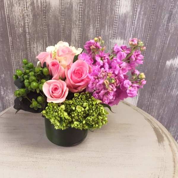Pink roses and purple flowers arranged in a black container