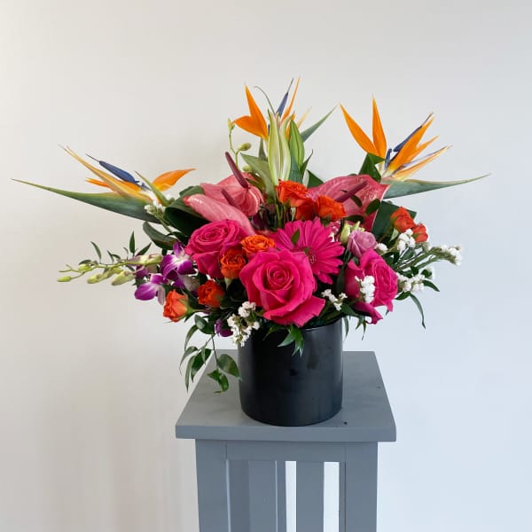Bright tropical bouquet with pink roses in a black vase