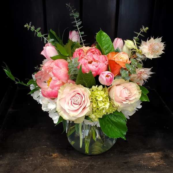 Pink and peach floral arrangement in a round glass vase