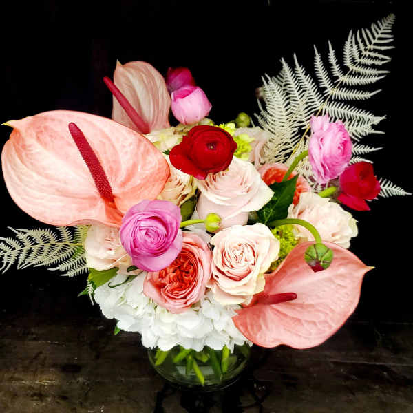 Pink anthuriums and mixed roses in a glass vase