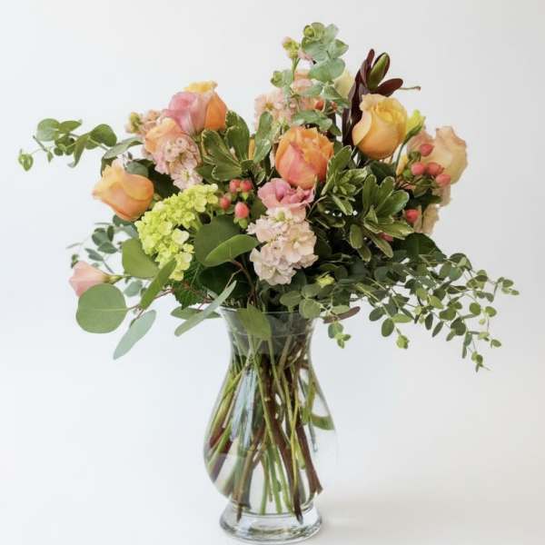 Mixed bouquet of peach and pink roses in a clear glass vase