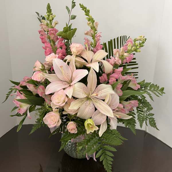 Pink lilies and roses arranged in a glass vase
