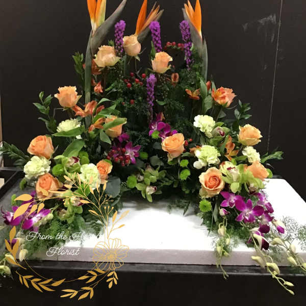 Large floral arrangement with orange roses and purple orchids on a white base
