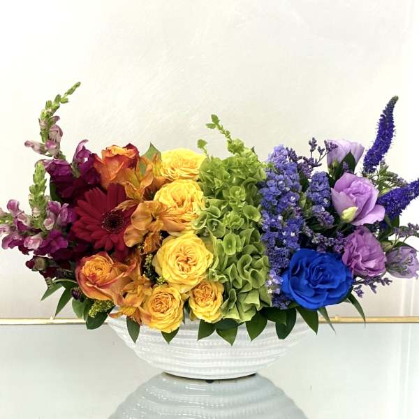 Colorful mixed flower arrangement in a white bowl vase