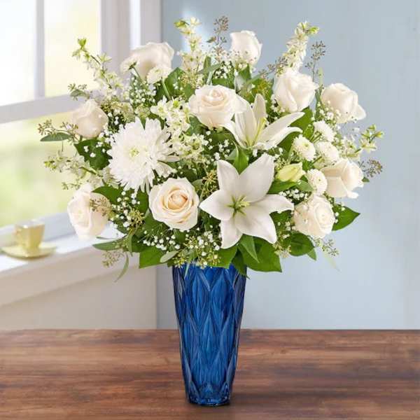White roses and lilies in a blue glass vase