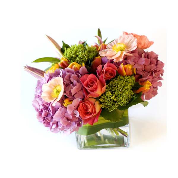 Mixed bouquet of pink and coral flowers in a clear glass vase