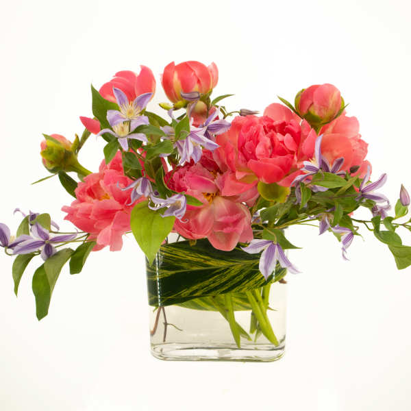 Pink flowers and purple blossoms arranged in a clear glass vase