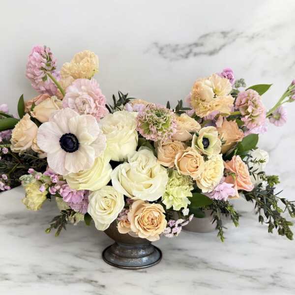 Pastel floral arrangement in a low pedestal vase with roses and anemones