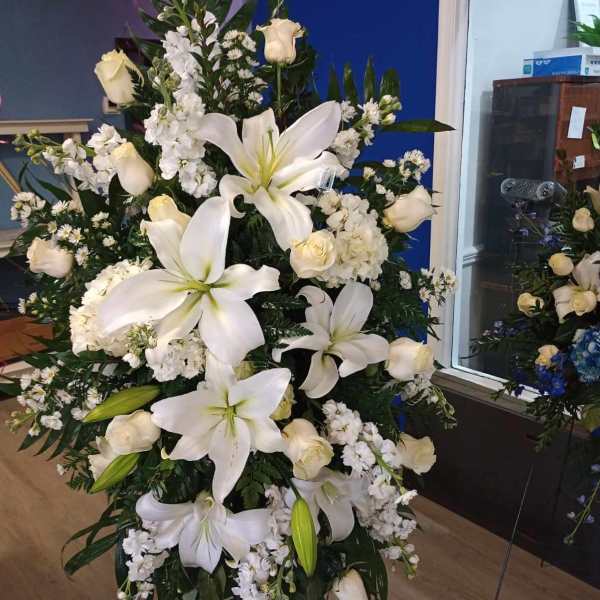 Large white funeral spray with lilies and roses on a stand