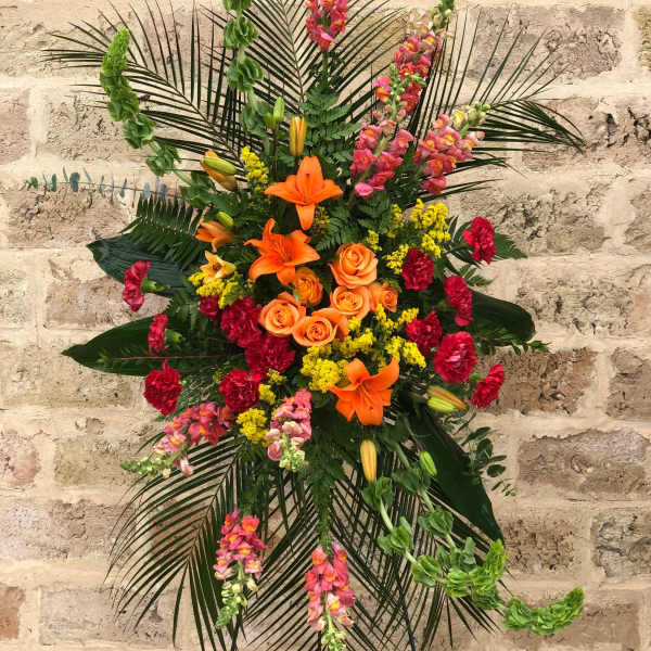 Tall floral standing spray with orange lilies, roses, and pink snapdragons