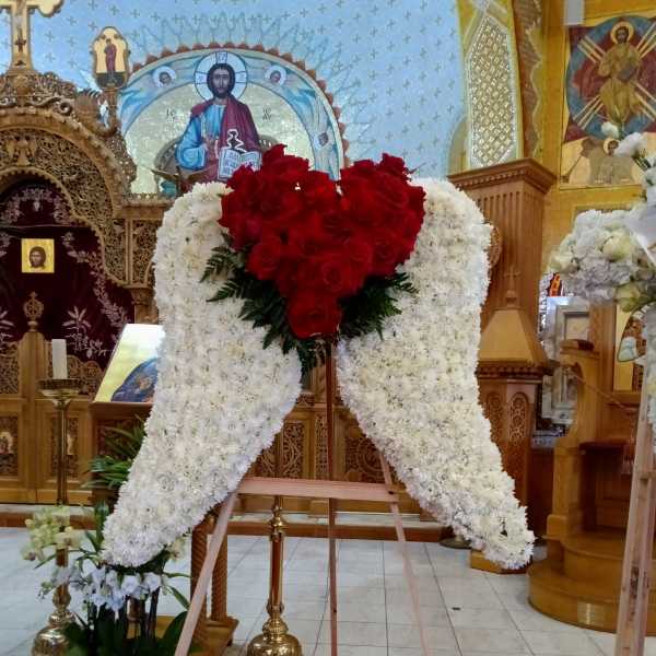 Large white floral standing spray with red roses in a church