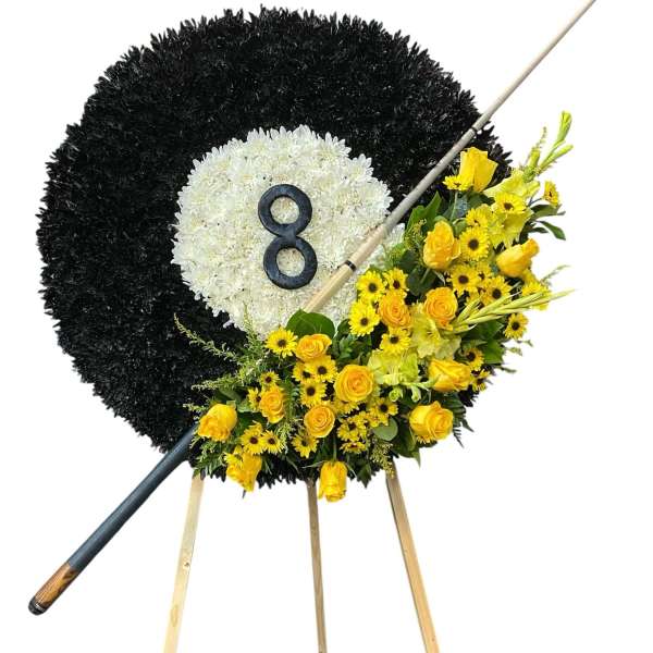 Black and white floral funeral wreath on an easel with yellow flowers