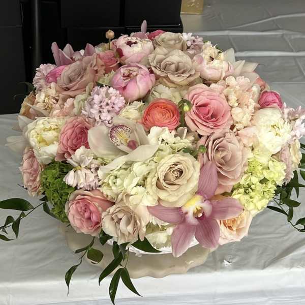 Large pastel bouquet of roses, orchids, and hydrangeas in a low vase