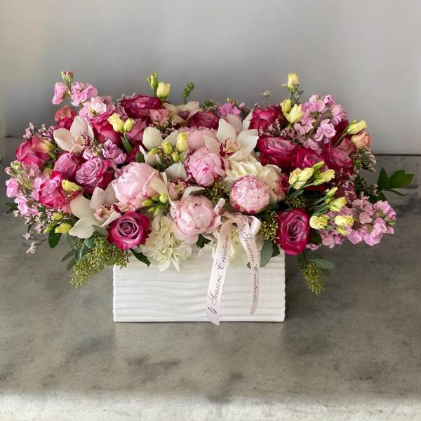 Pink and white floral arrangement in a white box with ribbon
