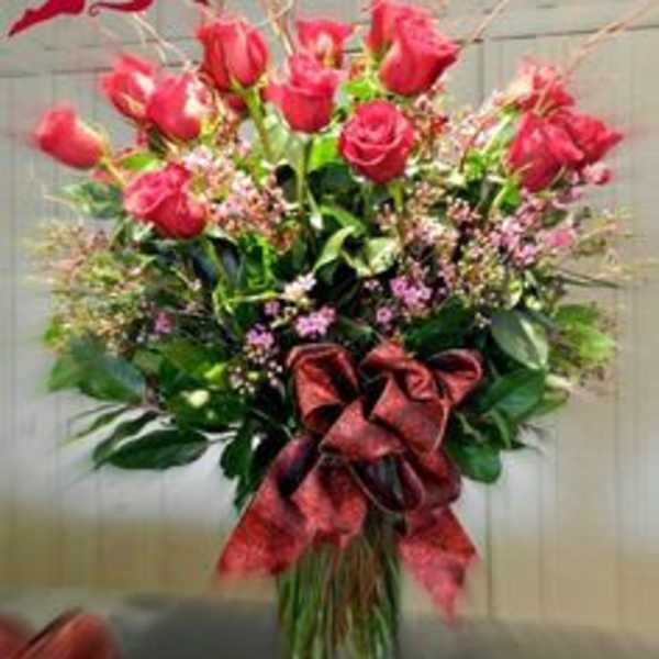 Tall bouquet of pink roses with a large red ribbon