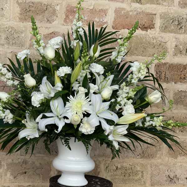 White lilies and roses arranged in a white urn vase