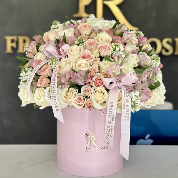Pink and cream roses arranged in a pastel pink box with ribbon