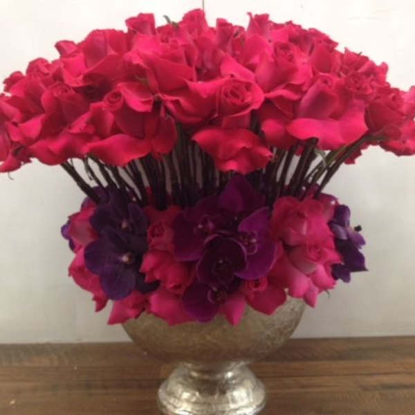 Large bouquet of hot pink roses and purple orchids in a silver vase