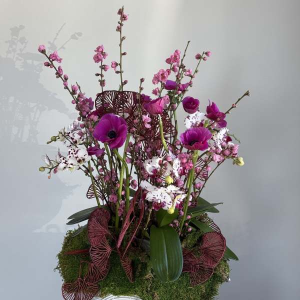 Pink and white orchid arrangement in a white bowl vase