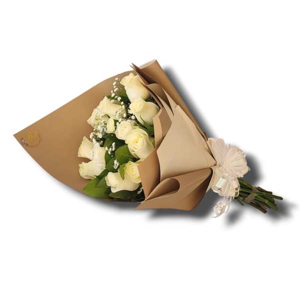 Hand-tied bouquet of white roses with filler flowers wrapped in tan paper and tied with a white ribbon bow