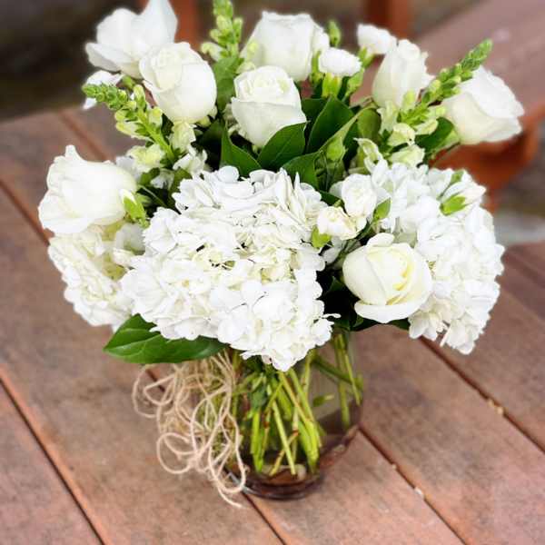 White roses and hydrangeas arranged in a glass vase