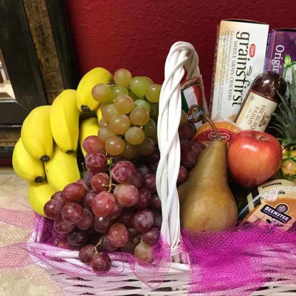 Fruit basket with bananas, grapes, pineapple, apple, pear, and packaged snacks