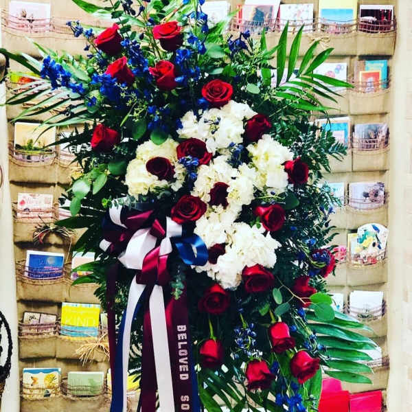 Standing floral spray with red roses, white blooms, and blue accents