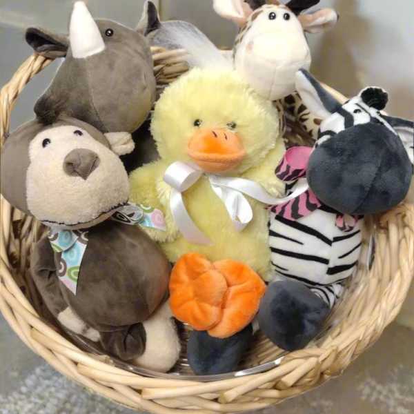 Basket of plush farm animals including a duck, cow, rhino, and dog