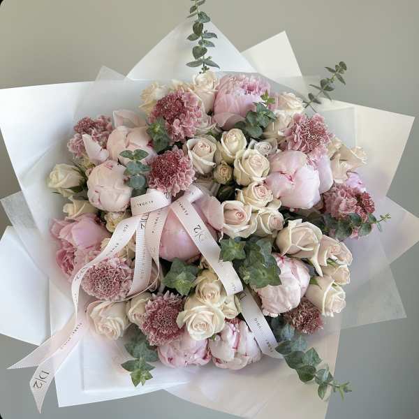 Bouquet of pale pink peonies and cream roses with ribbon wrap