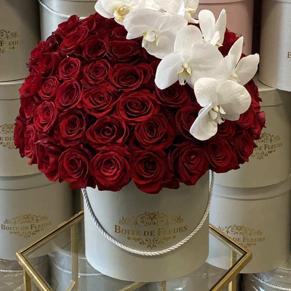Red roses with white orchids in a round hat box
