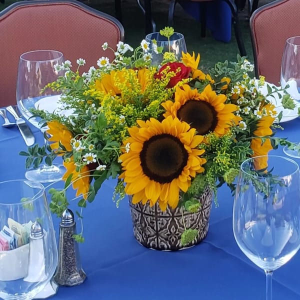 Sunflower centerpiece in a patterned pot on a blue tablecloth