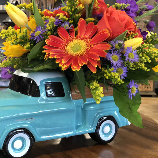 Colorful flower arrangement in a turquoise ceramic truck container