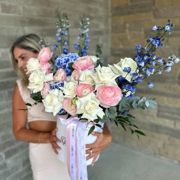 Bouquet of white and pink roses with blue flowers in a white box