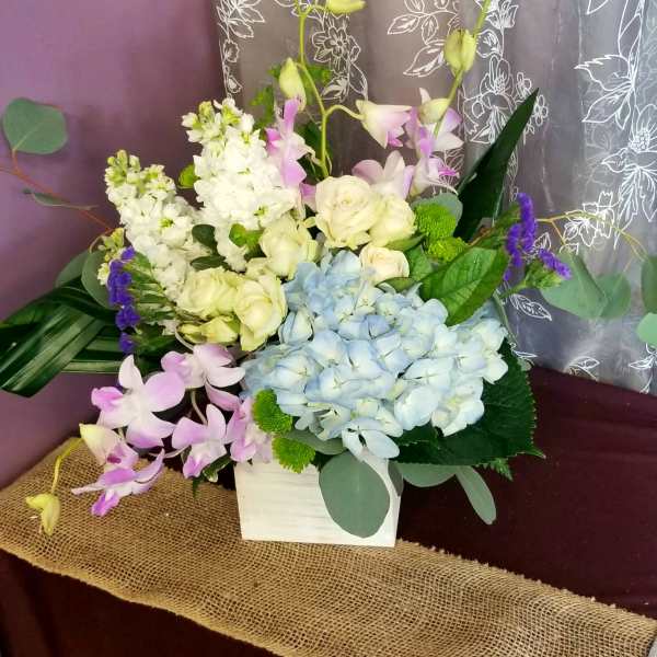 Mixed bouquet with blue hydrangea, white roses, and pink orchids in a white box