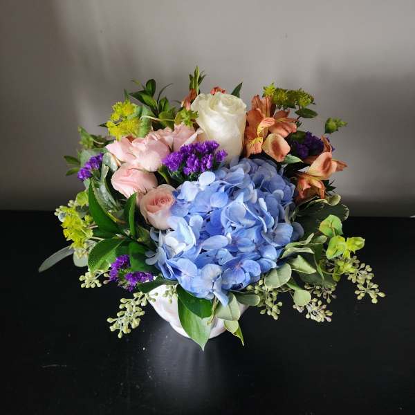 Mixed bouquet with blue hydrangea, pink roses, and white rose in a white vase