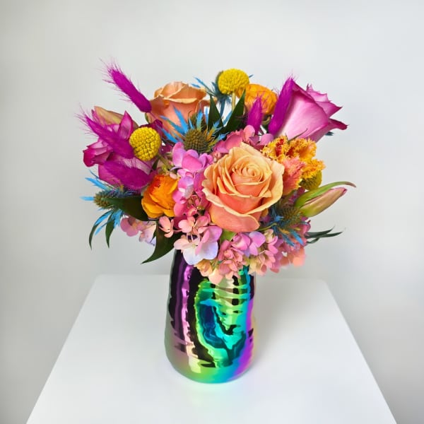 Colorful bouquet of mixed flowers in a rainbow metallic vase