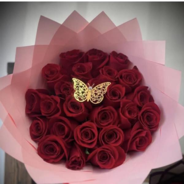 Bouquet of red roses wrapped in pink paper with a butterfly decoration