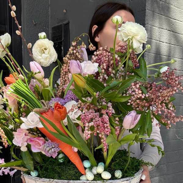 Large spring bouquet in a woven basket with pastel flowers and speckled eggs