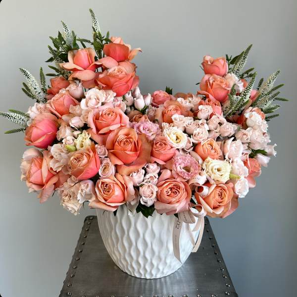 Large peach and blush rose arrangement in a white vase