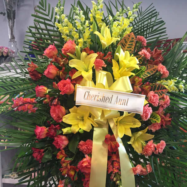 Large floral standing spray with yellow lilies and pink-orange flowers