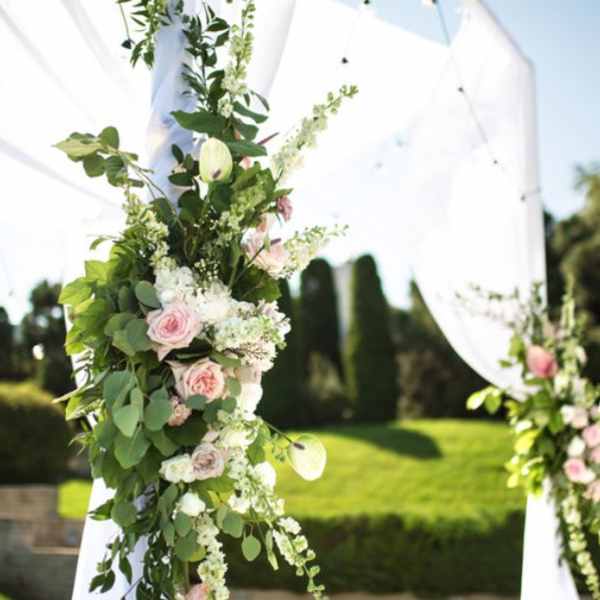 Floral garland on a white wedding arch with pink roses and greenery