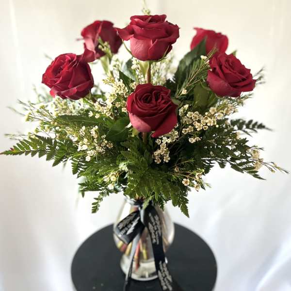 Red roses arranged in a clear glass vase with white filler flowers