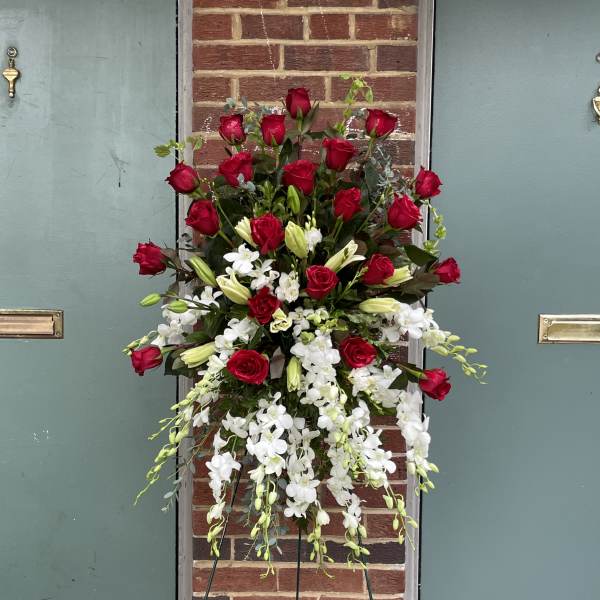 Tall standing floral spray with red roses and white orchids on a metal easel