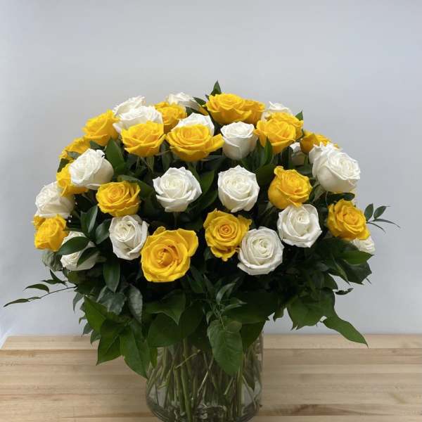 Bouquet of yellow and white roses in a clear glass vase