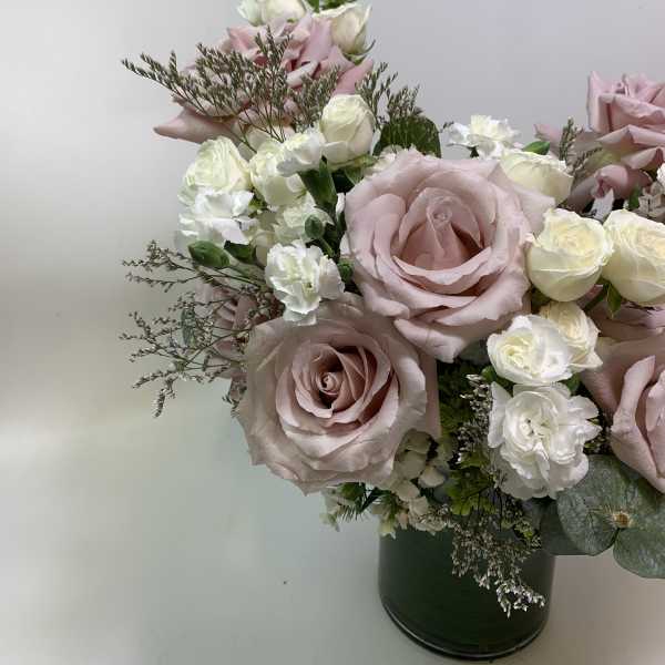 Pink and white roses arranged in a dark vase