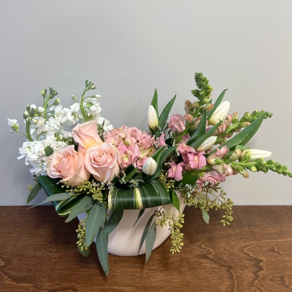 Pink roses and white flowers arranged in a white vase