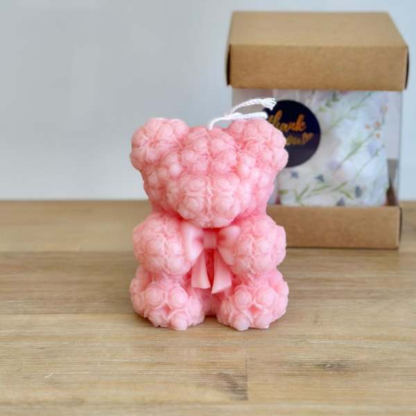 Pink teddy bear made of roses with a ribbon, shown in front of a gift box