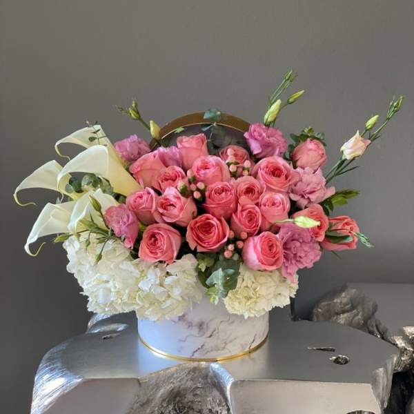 Pink roses and white hydrangeas arranged in a round box
