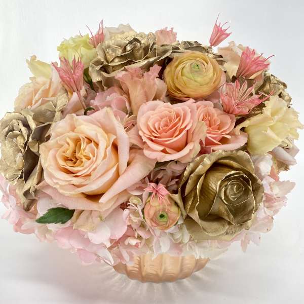 Bouquet of blush and gold roses in a peach vase