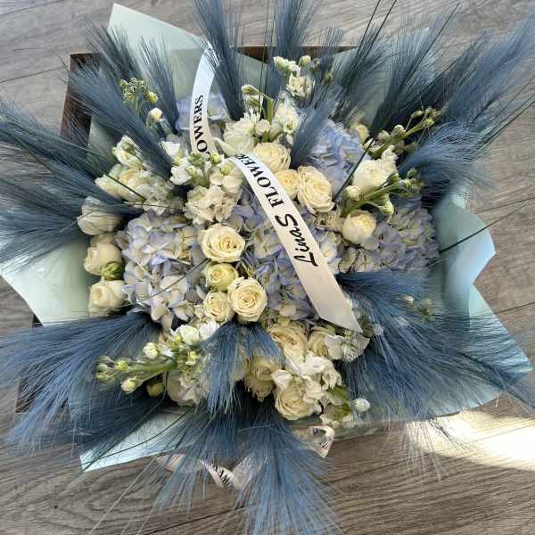Bouquet of white roses and pale blue hydrangeas with blue feathery accents